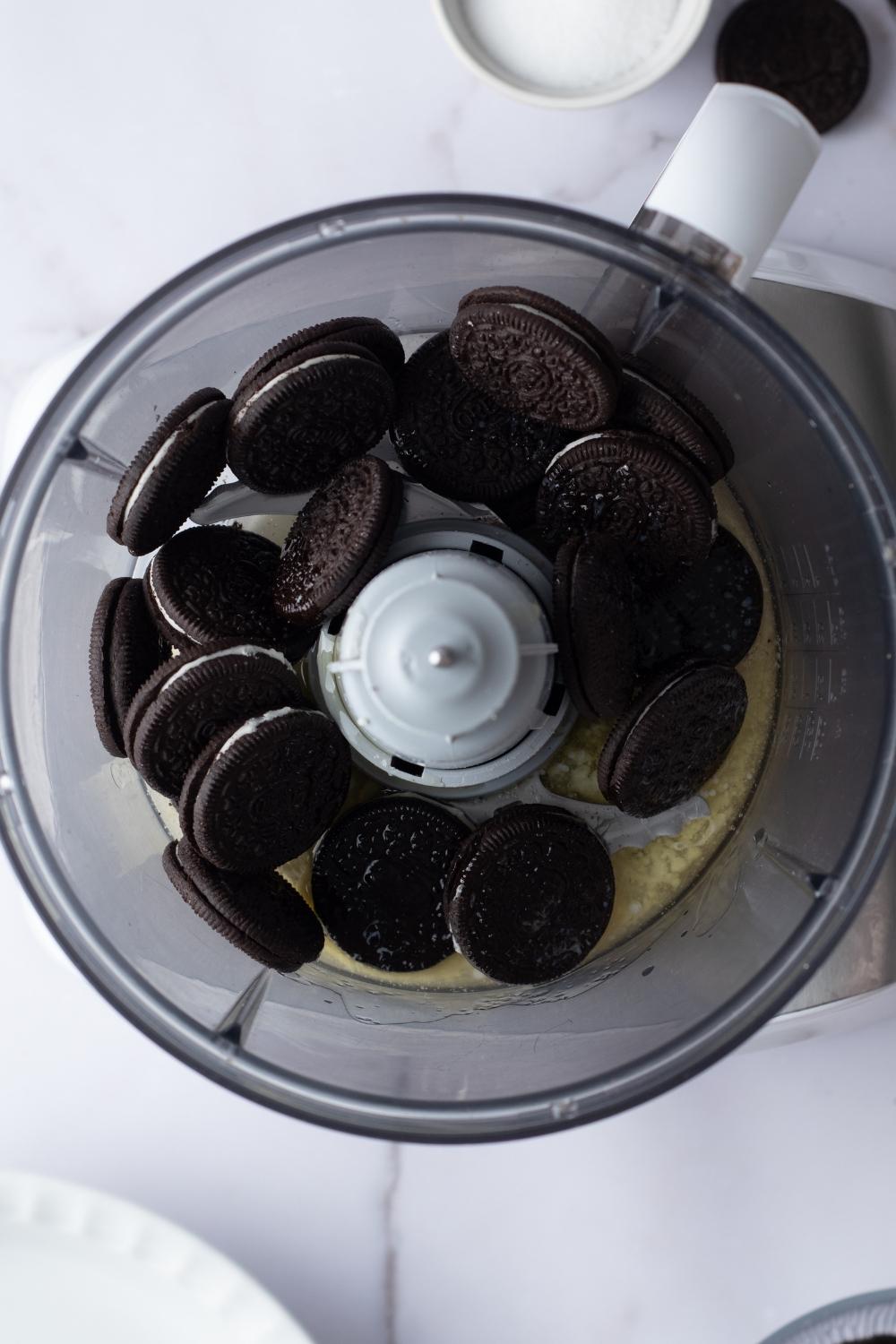 An overhead view of melted butter and oreos in a food processor.