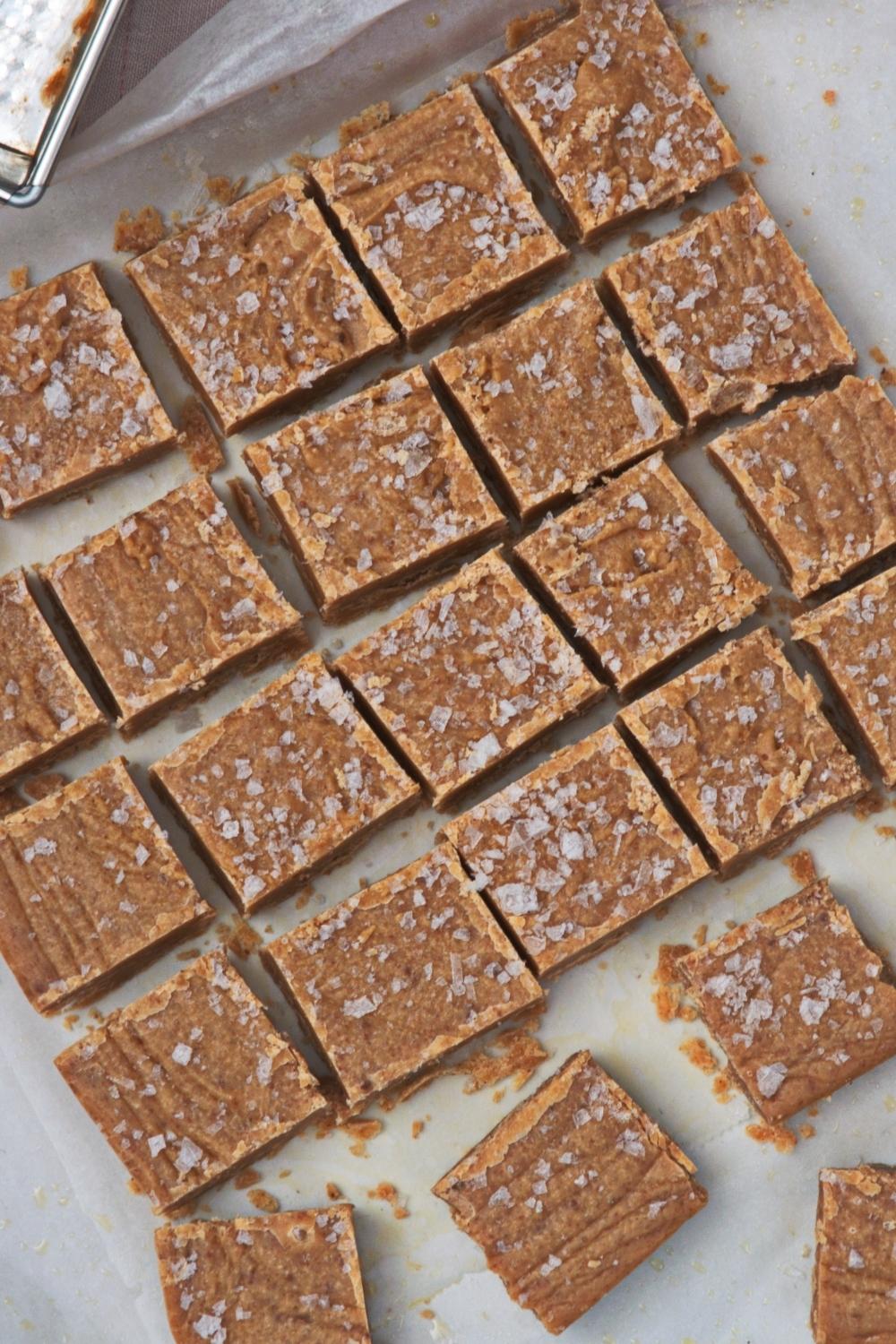 An overhead view of a square shape of caramel fudge that is cut into many small squares.