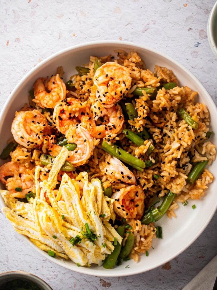 An overhead, close up view of a bowl of Cajun Fried Rice with green beans, shrimp, and egg.