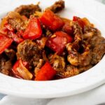 A white bowl that is filled with beijing beef.