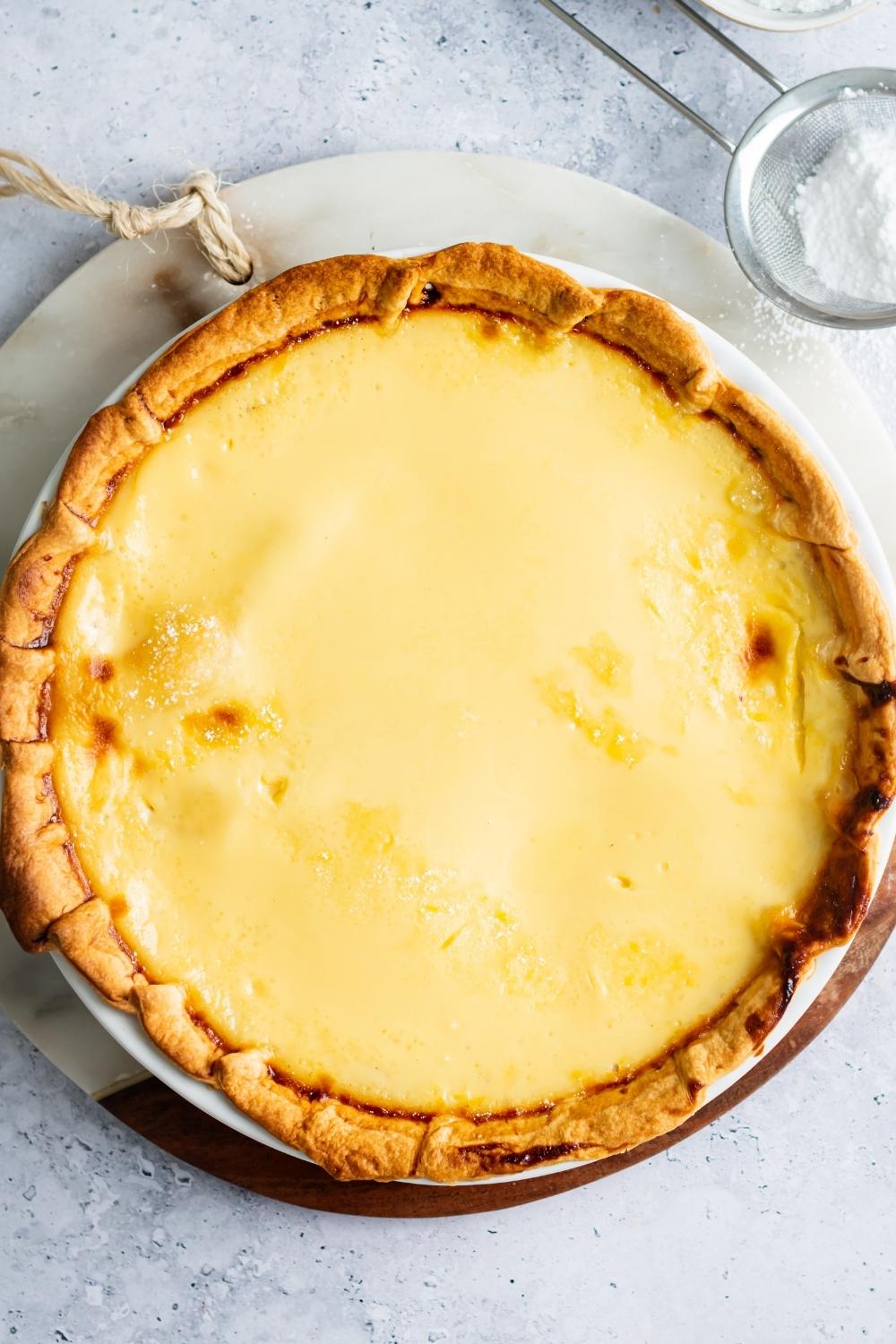 An overhead view of a custard pie fresh out of the oven with golden brown crust and cooked custard filling.