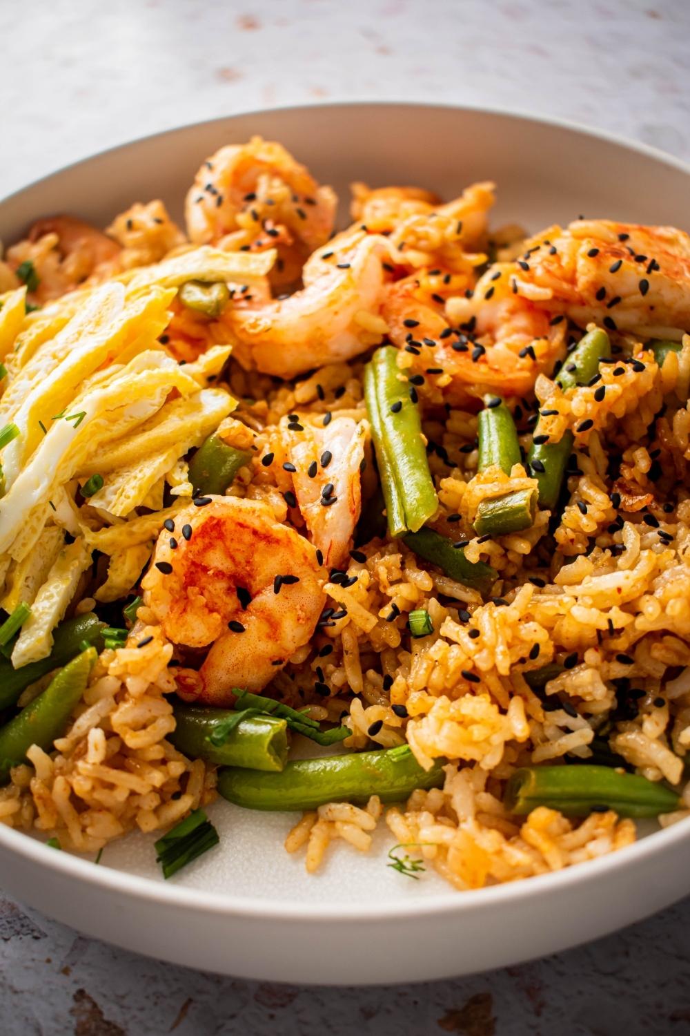 A close up of a bowl of Cajun Fried Rice with green beans, shrimp, and egg.