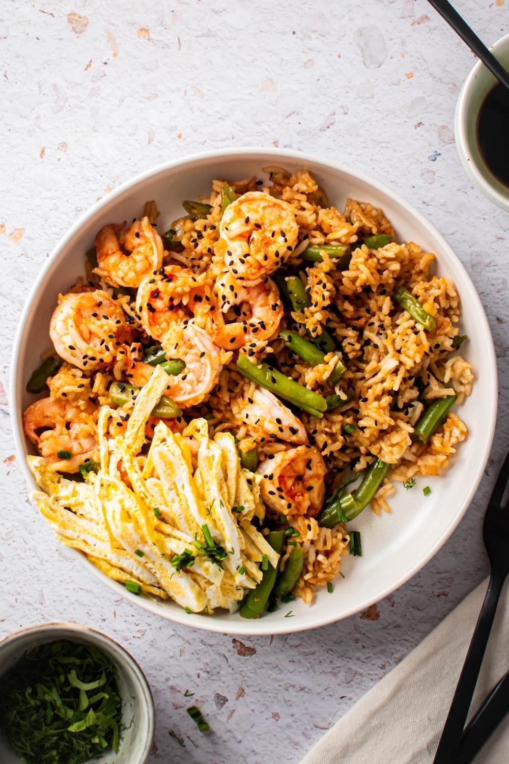 An overhead view of a bowl of Cajun Fried Rice with green beans, shrimp, and egg.