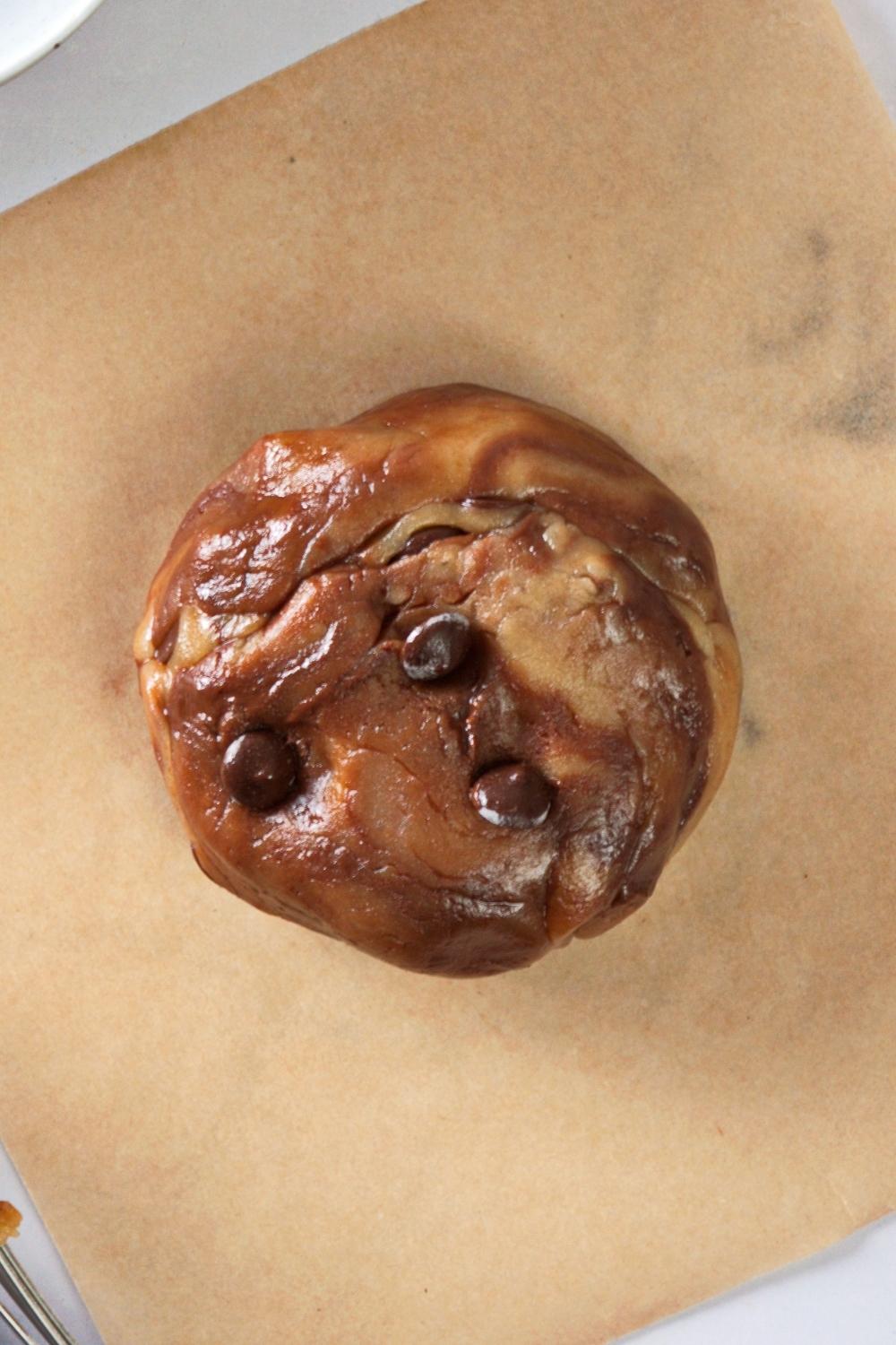 An overhead view of a ball of cookie dough on a piece of parchment paper.