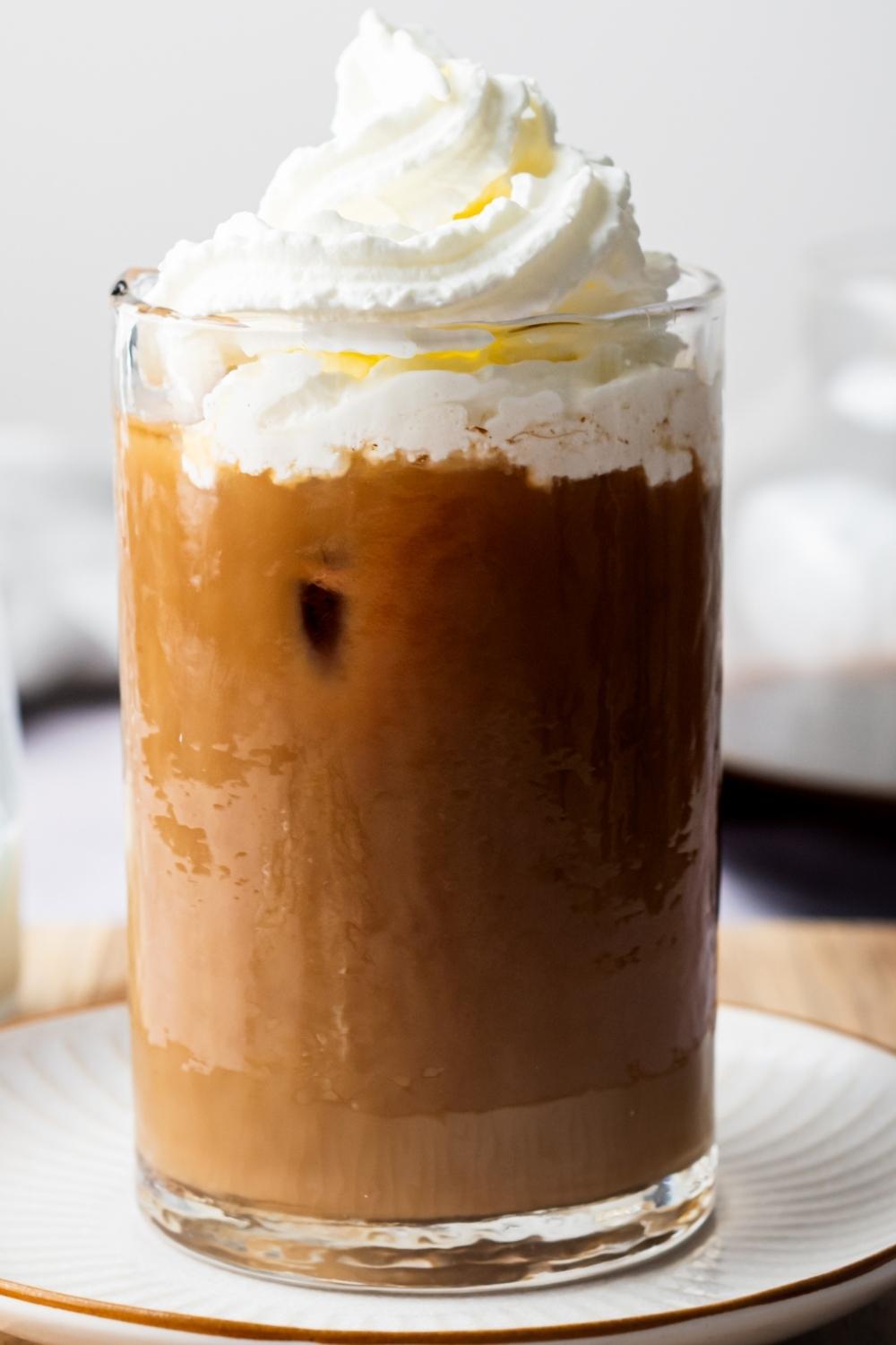 A side view of homemade McDonald's iced coffee topped with whipped cream in a glass.