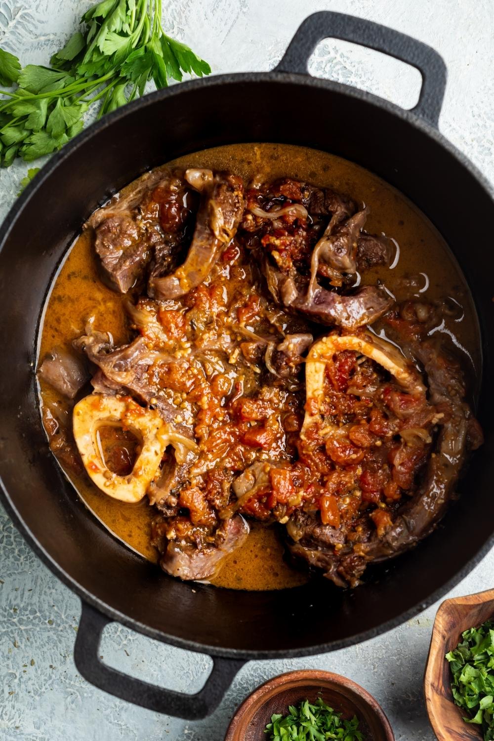 A dutch oven filled with beef shank and sauce ingredients.