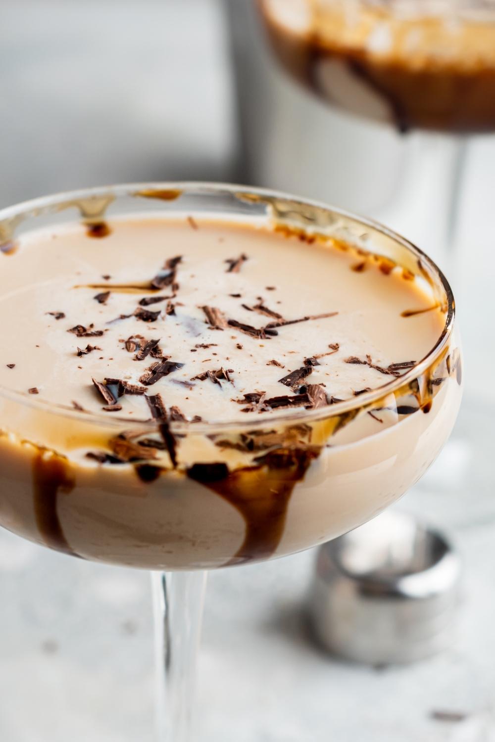 A close-up view of a mudslide cocktail in a cocktail stemmed glass. It is garnished with shaved chocolate and there is drizzled chocolate on the inside of the glass.