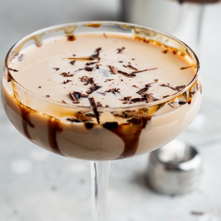 Close up overhead view of a mudslide cocktail in a cocktail stemmed glass. It is garnished with shaved chocolate and there is drizzled chocolate on the inside of the glass.