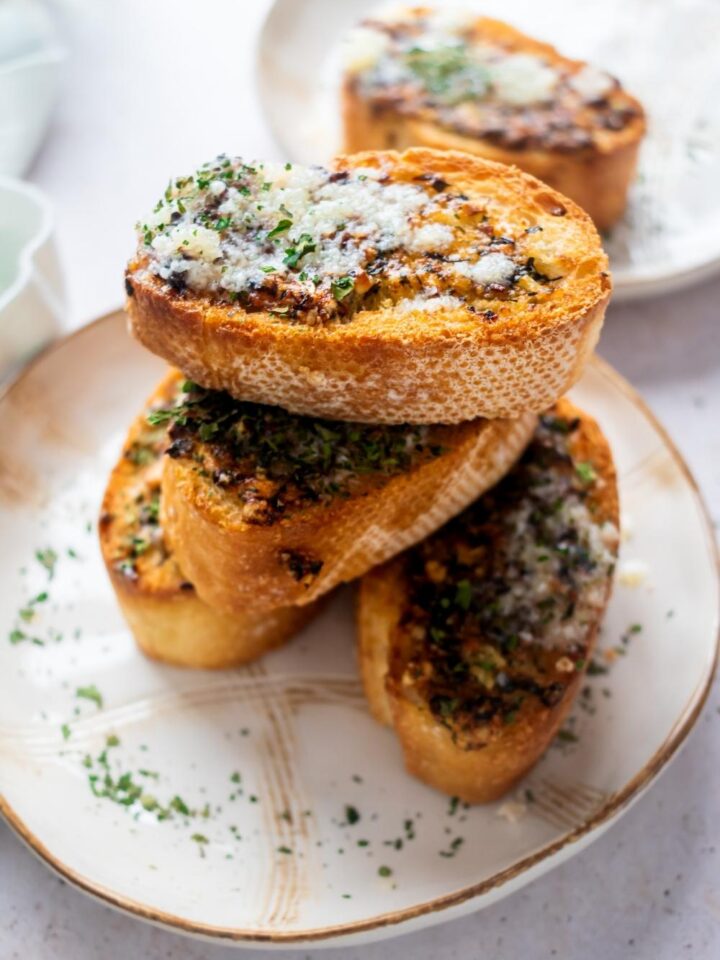 Two pieces of garlic bread stacked on top of two pieces of garlic bread on a white plate.