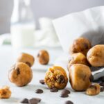 A bunch of edible cookie dough balls on a grey counter.
