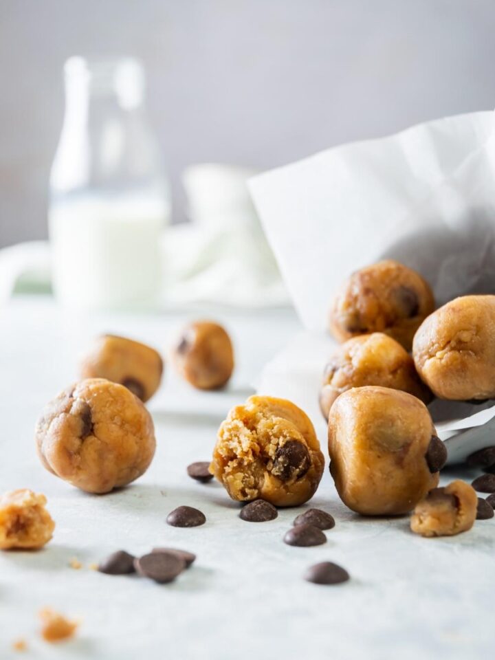 A bunch of edible cookie dough balls on a grey counter.