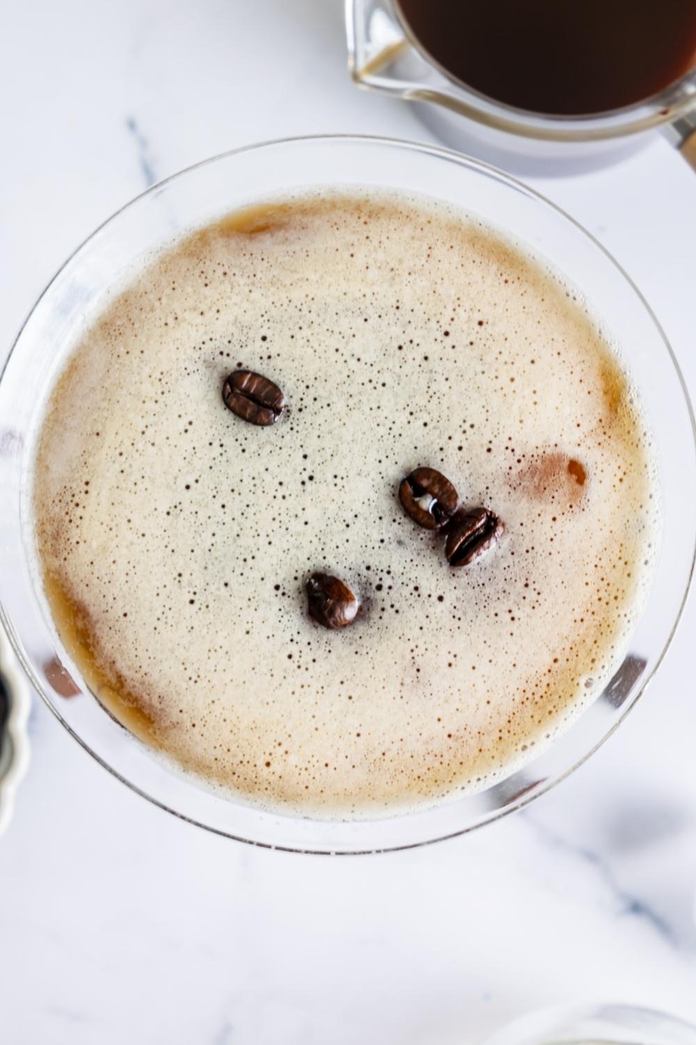 An overhead view of a martini glass with homemade espresso martini garnished with espresso beans.
