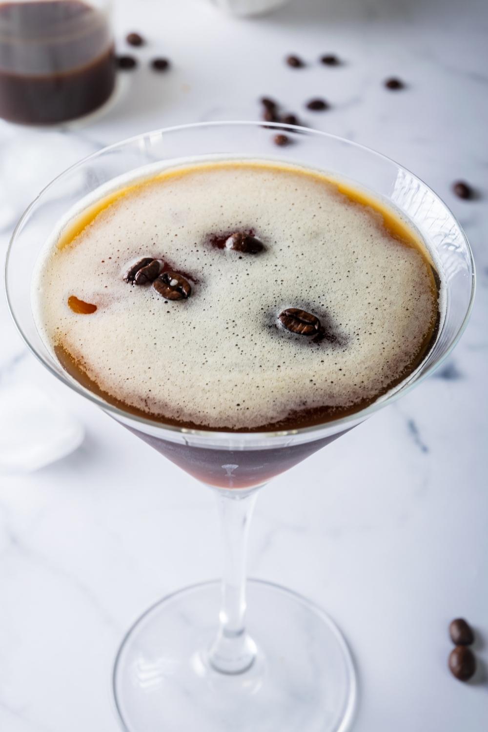 A martini glass with homemade espresso martini garnished with espresso beans.