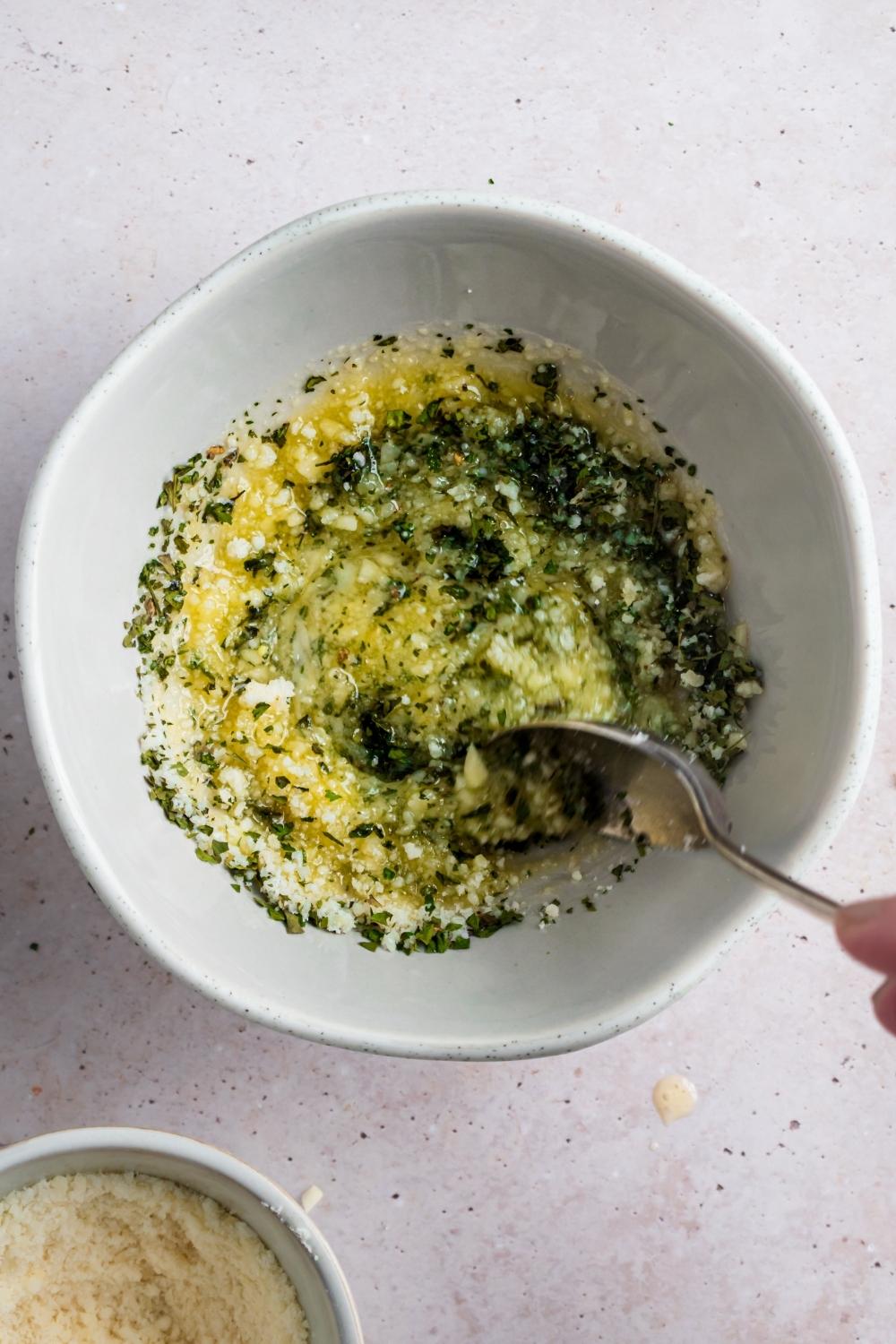 A spoon mixing minced garlic and melted butter together.