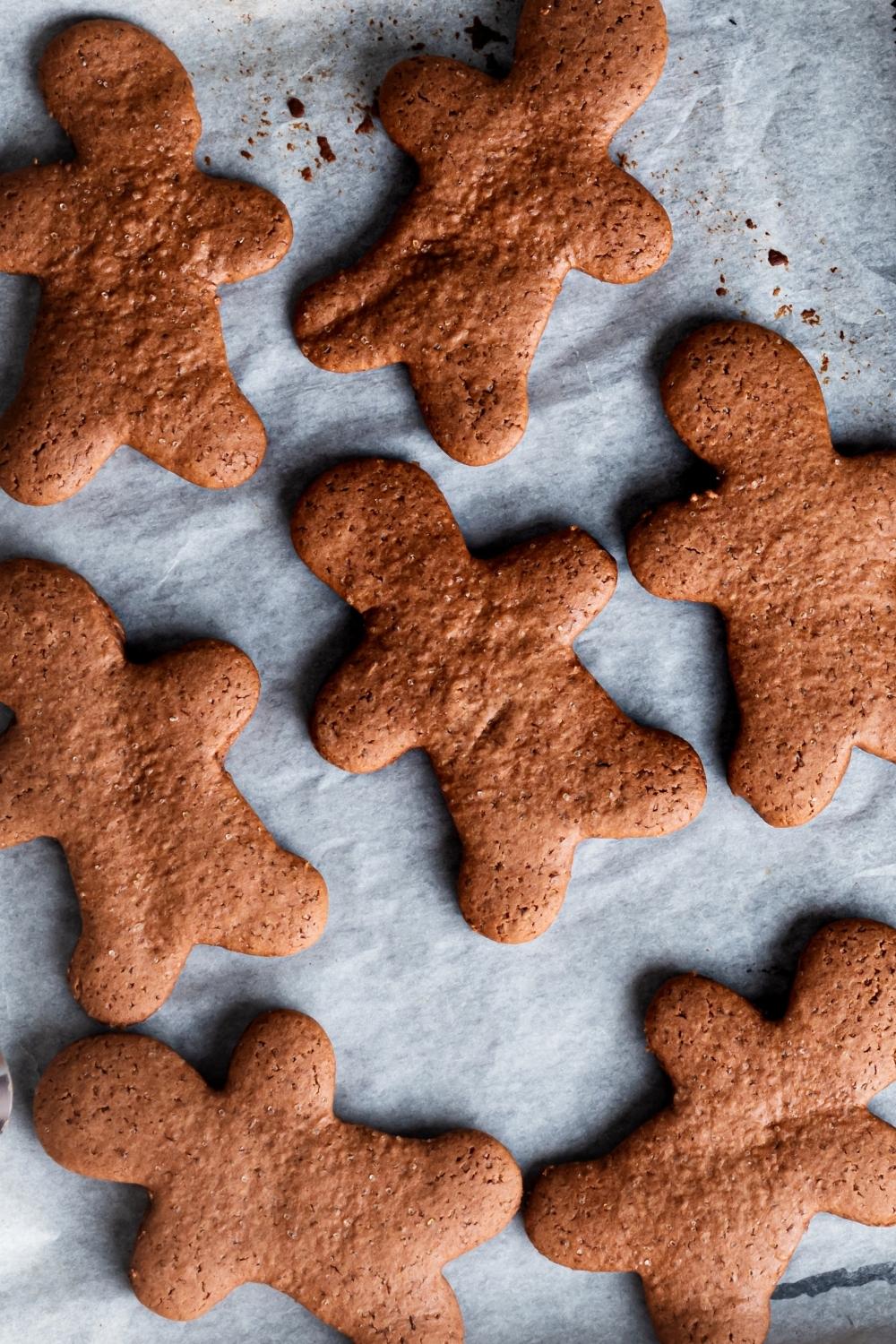 An overhead view of baked homemade gingerbread cookies on a parchment lined tray.