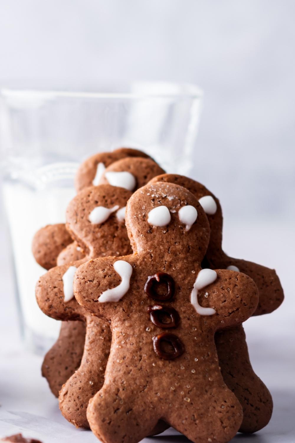 A stack of homemade gingerbread cookies proped up by a glass of milk on a countertop.