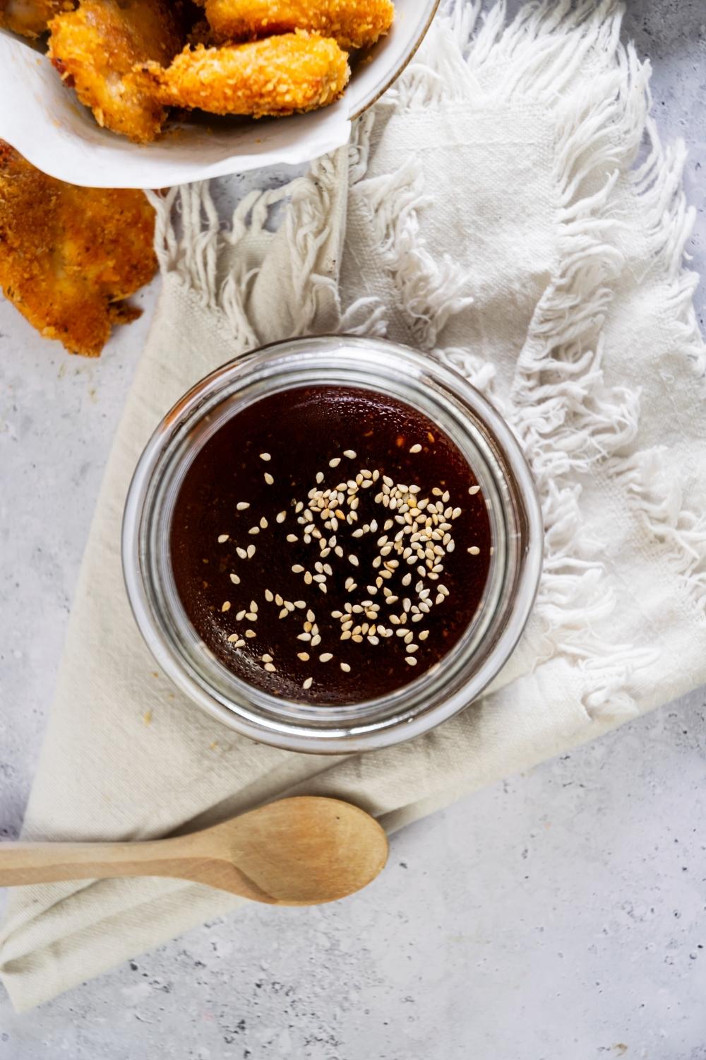 Sesame seeds on top of a glass jar that has szechuan sauce in it.