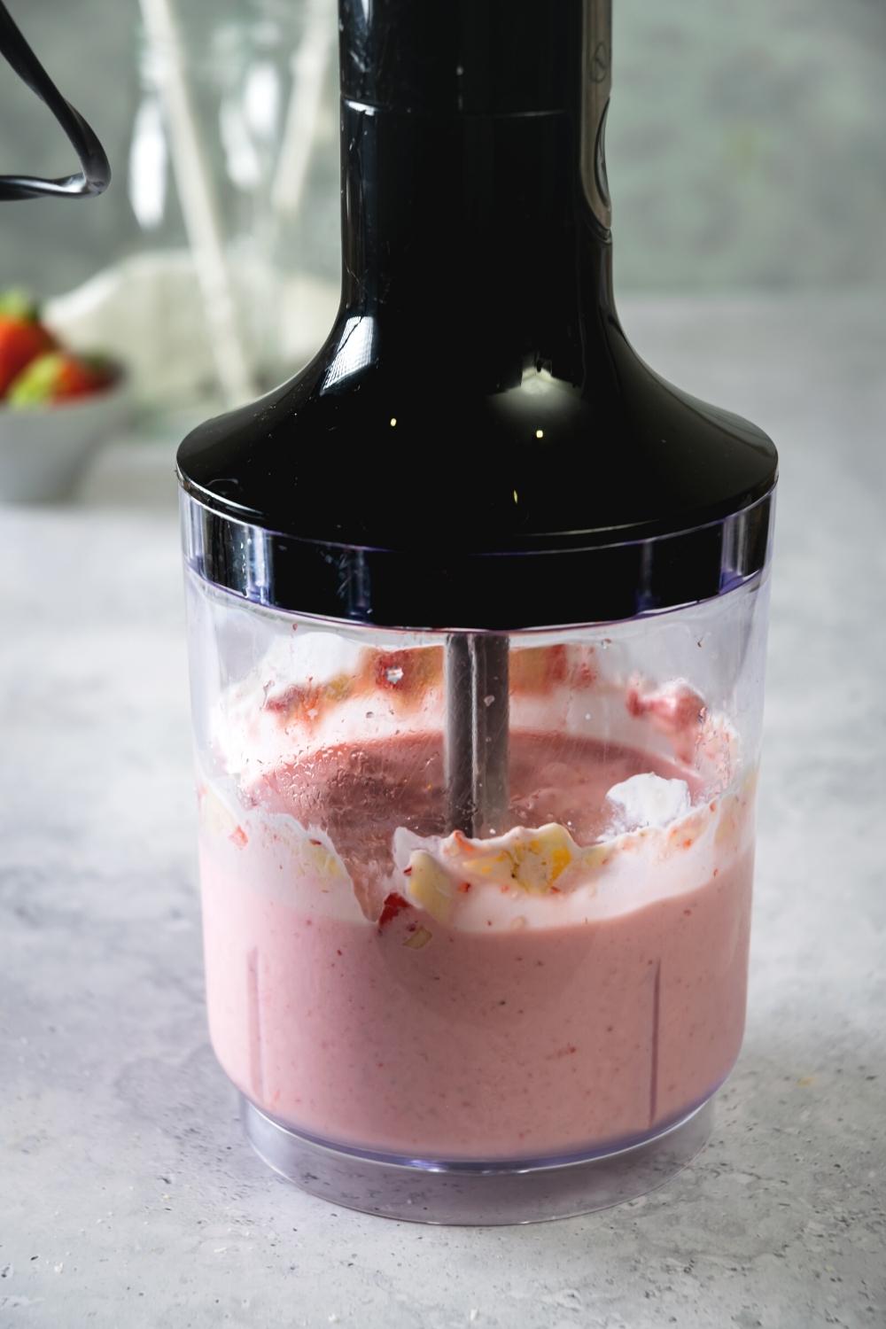 A blender that has a strawberry banana smoothie in it.