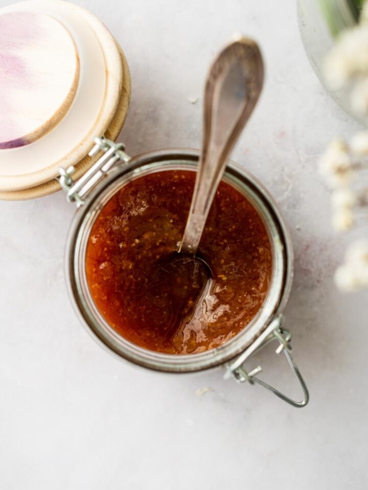 A glass jar that is filled with sweet and sour sauce ingreidents.