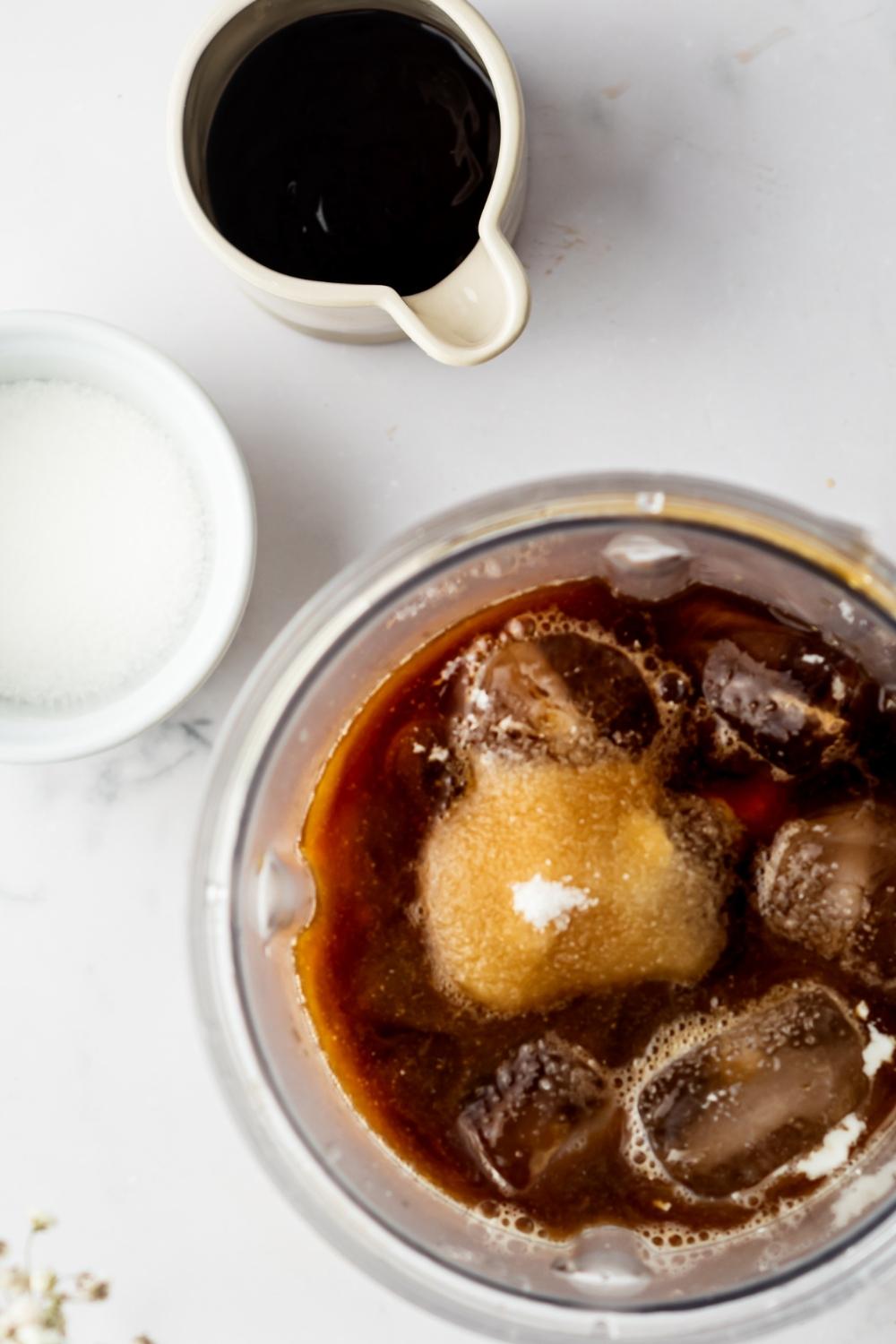 An overhead hue of a picture with black coffee, ice cubes, and sugar.