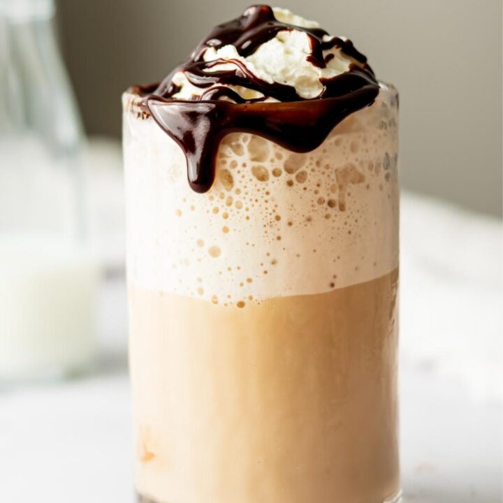One glass of McDonald's mocha frappe topped with whipped cream on a countertop.