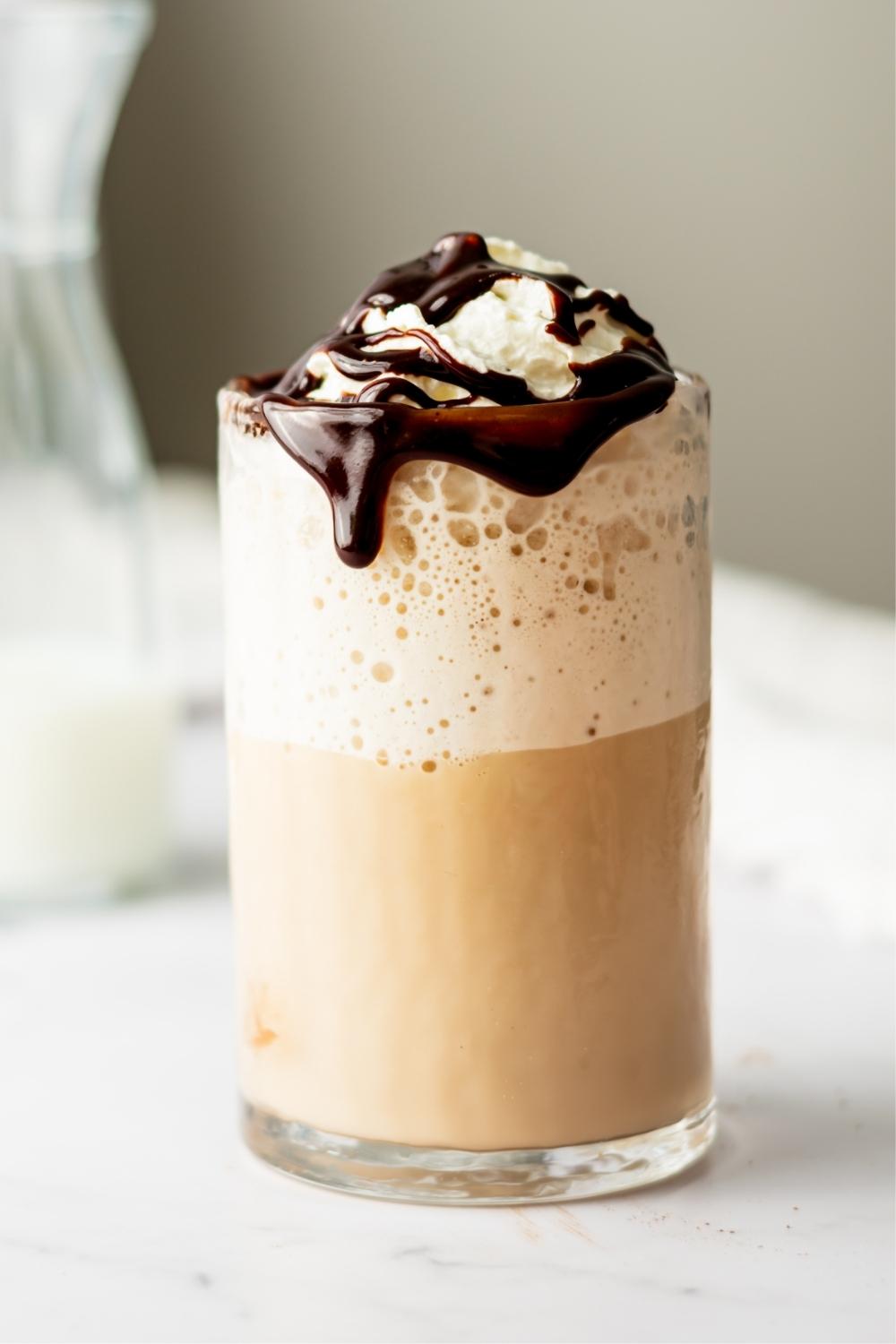 One glass of McDonald's mocha frappe topped with whipped cream on a countertop.