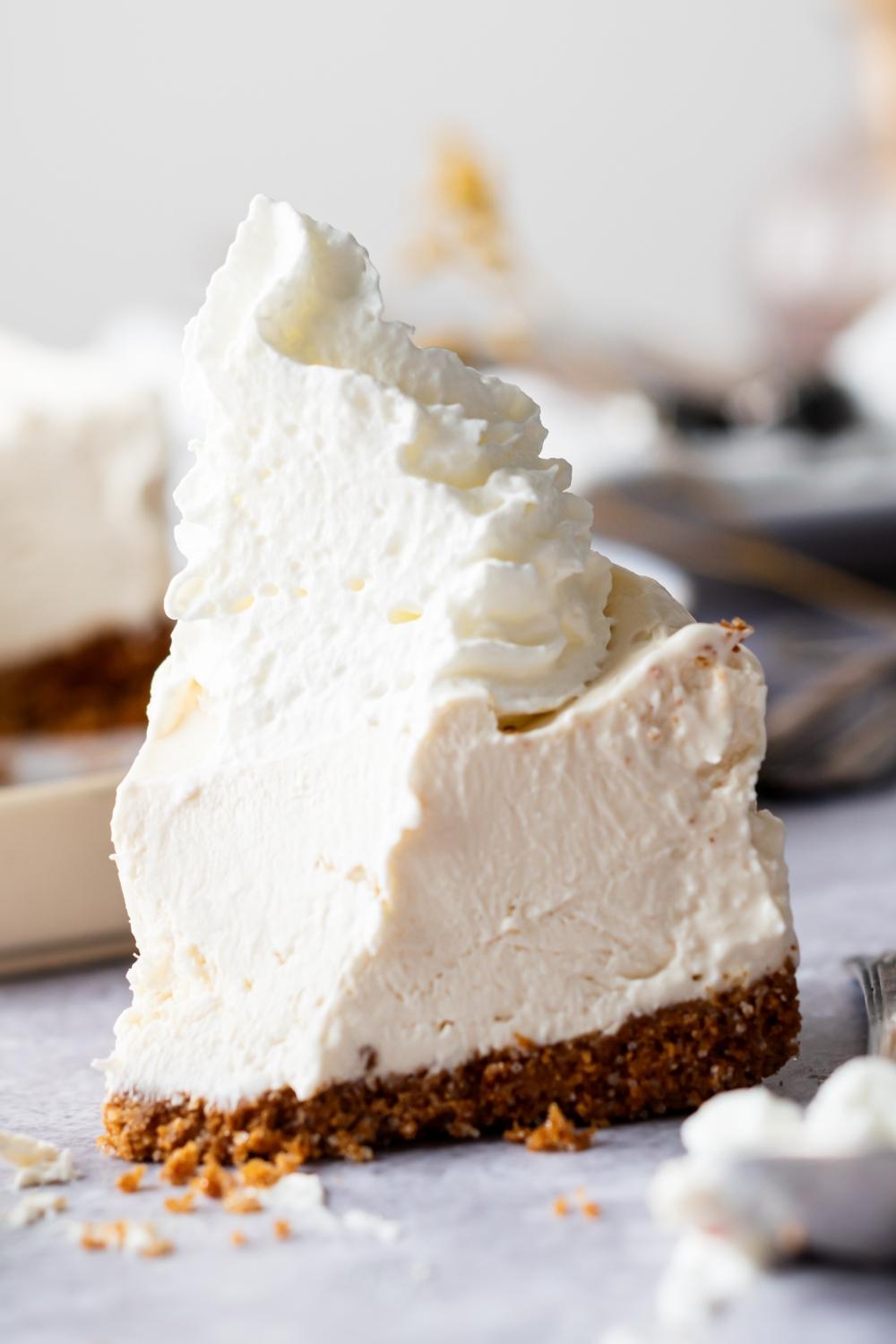 A slice of cheesecake with a dollop of whipped cream on top.