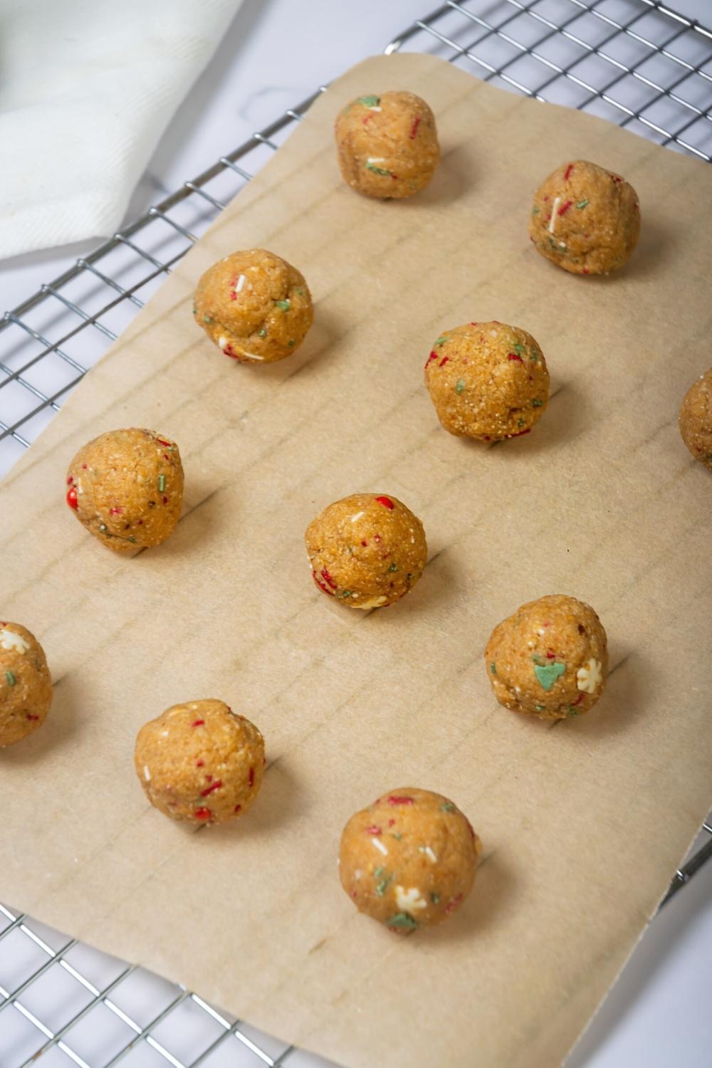 Three rows of four no bake peanut butter balls on a piece of parchment paper on a wire rack.