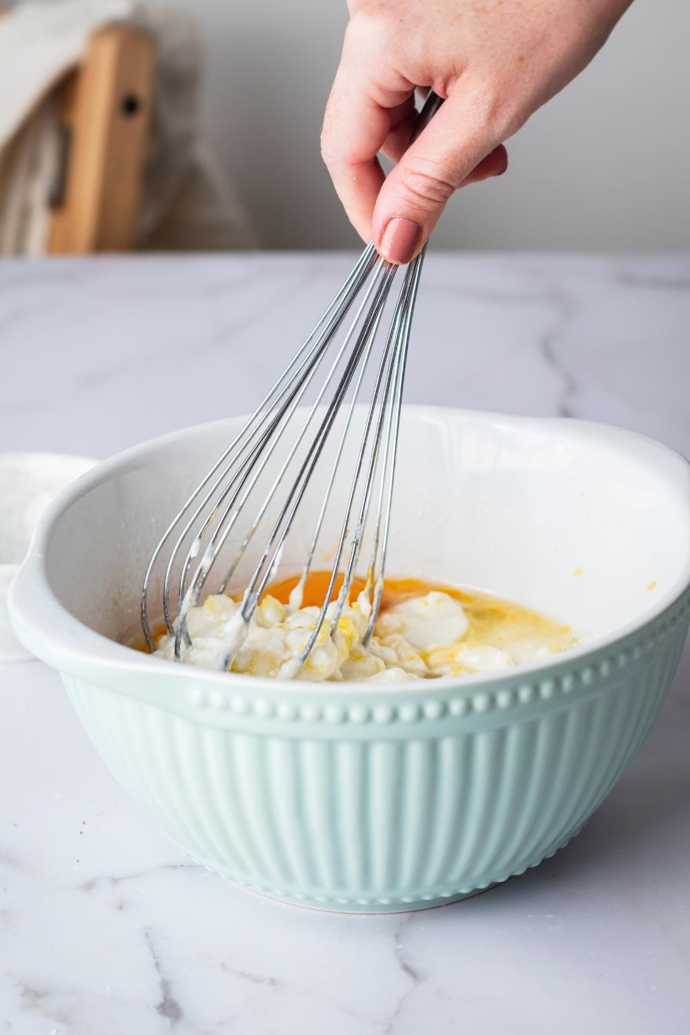 A hand whisking together ricotta pie filling ingredients.
