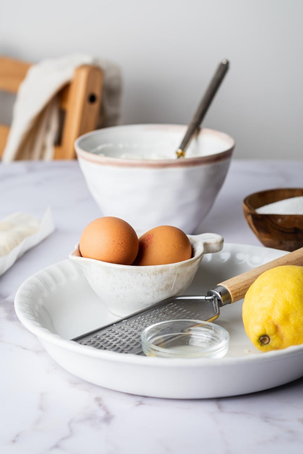 Two eggs in bowl in a pie dish with a lemon.