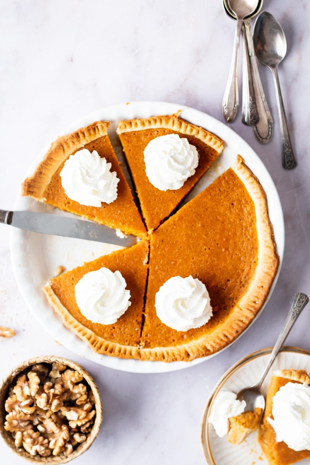 A sweet potato pie that has three slices cut and the rest of it uncut on a plate.