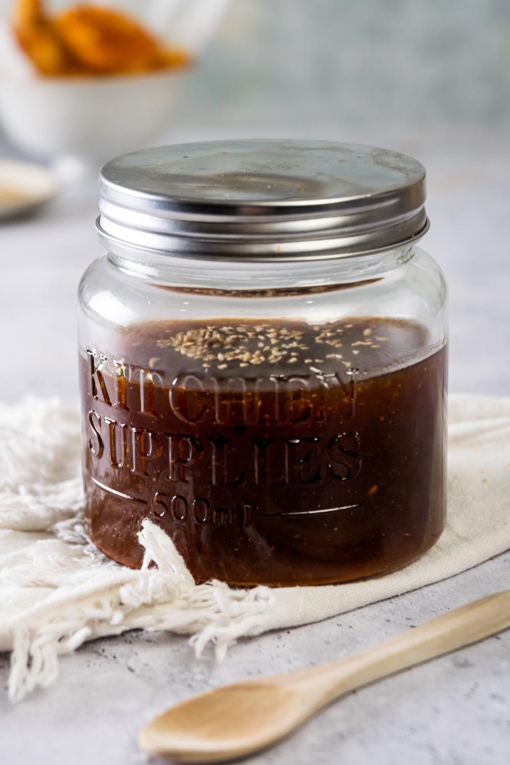 A glass jar with szechuan sauce in it and a lid on top.