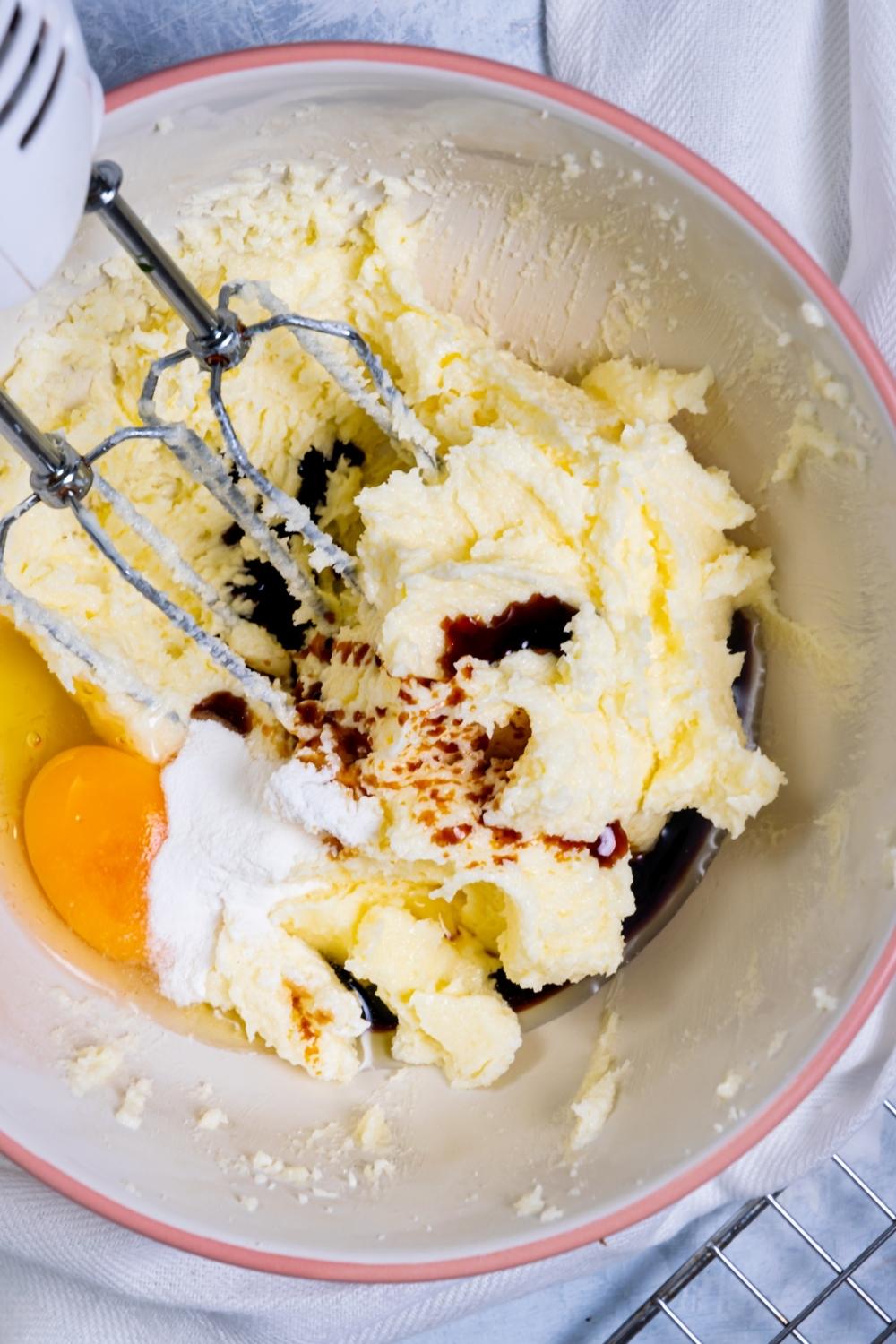 A mixing bowl with cream butter and sugar, vanilla, and egg.
