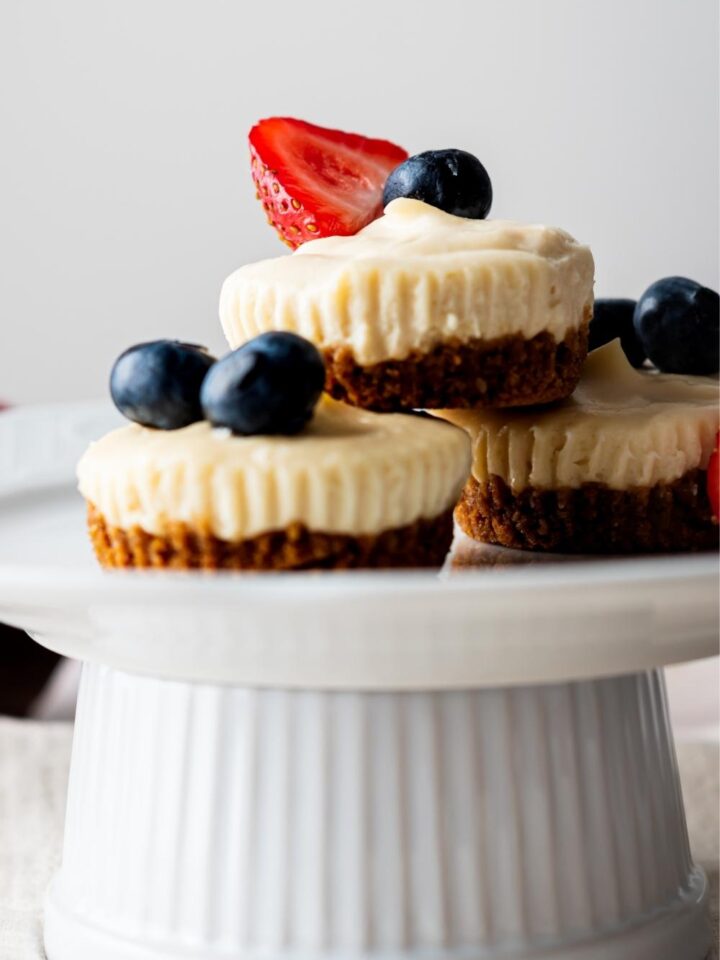 A cake stand with homemade mini cheesecake bites topped with berries.