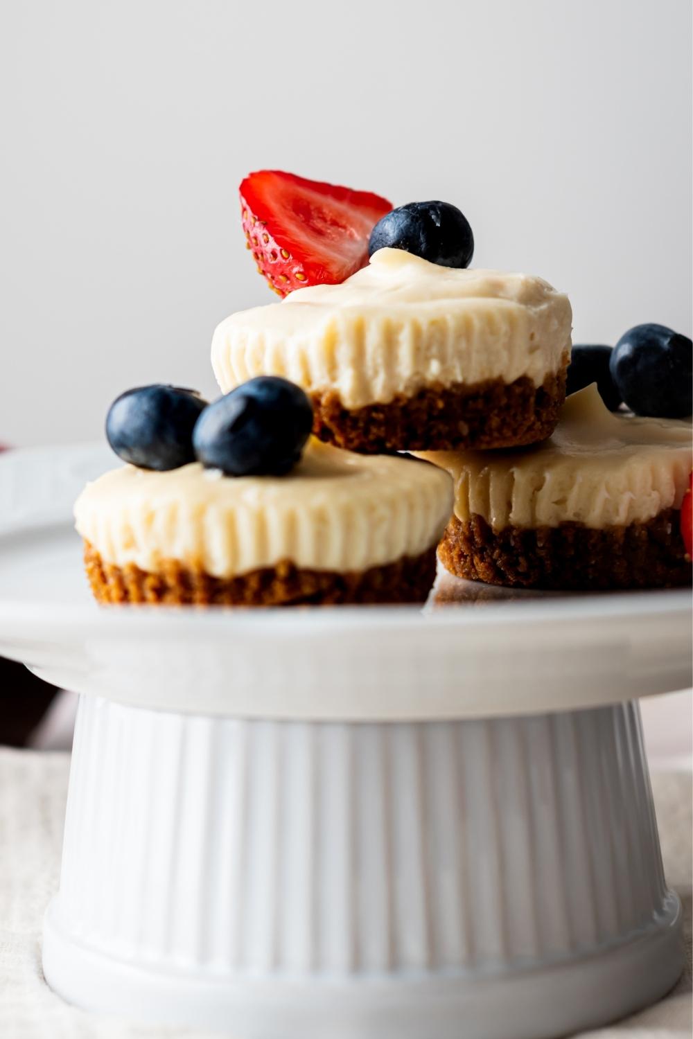 A cake stand with homemade mini cheesecake bites topped with berries.
