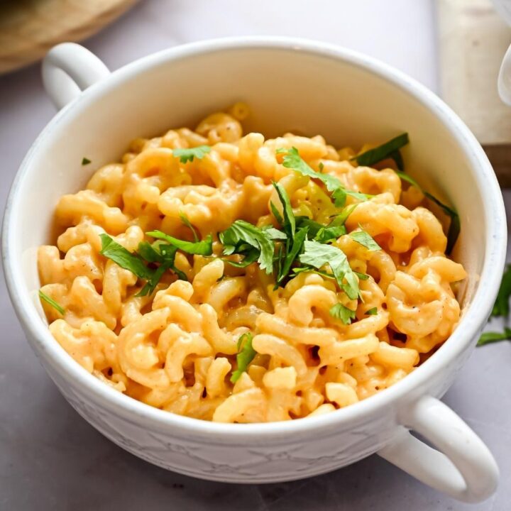 A serving bowl with homemade outback steakhouse mac & cheese garnished with parsley leaves.