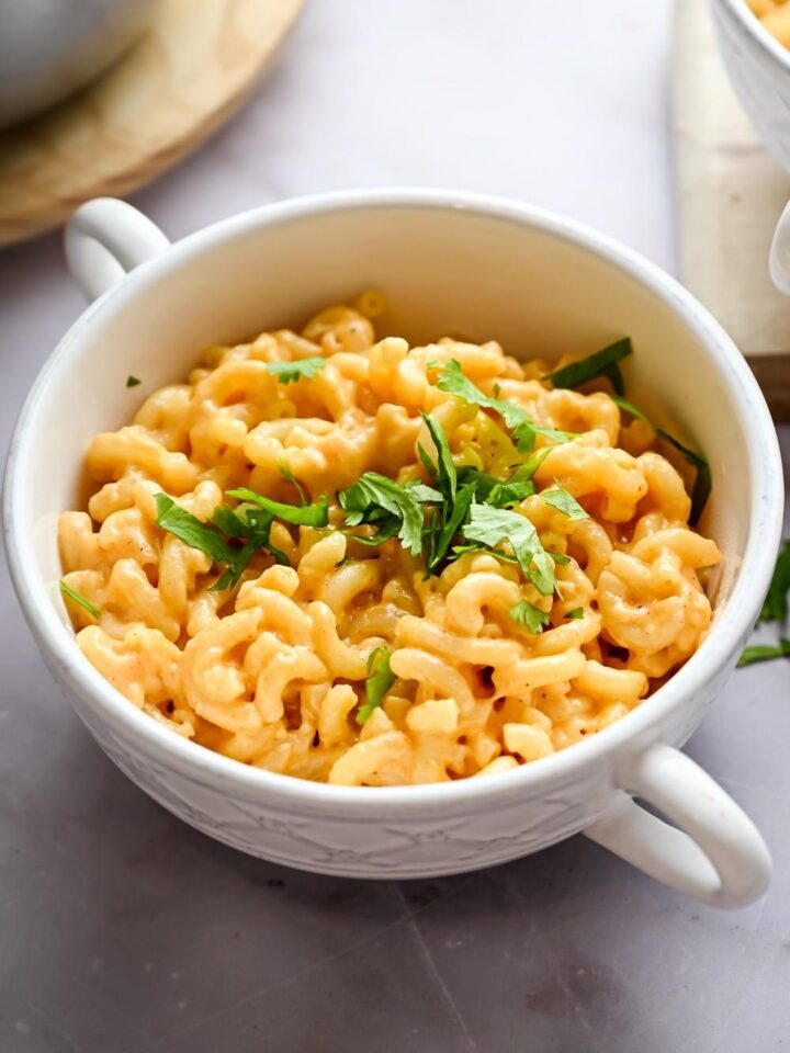 A serving bowl with homemade outback steakhouse mac & cheese garnished with parsley leaves.