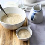 a small bowl of white gravy next to a large bowl of white gravy