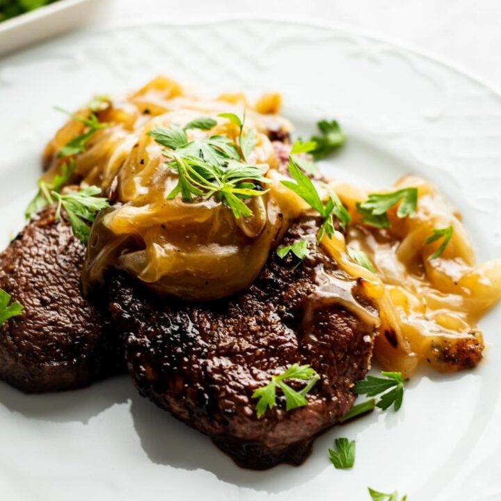 cubed steak with onion gravy and parsley on a white plate