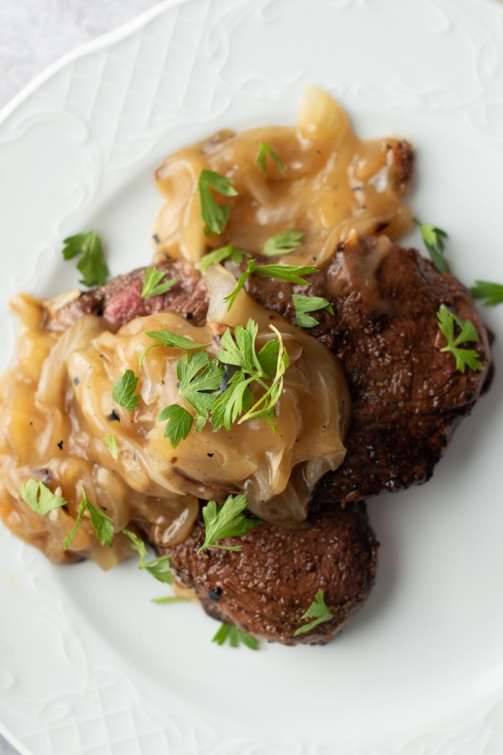 top shot of cubed steak with onion gravy and parsley on a plate