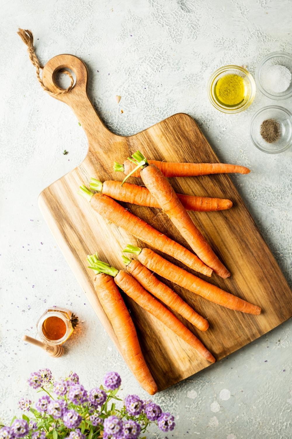 raw trimmed carrots on a wooden cutting board