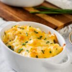 Cheesy mashed potatoes in a white casserole dish.