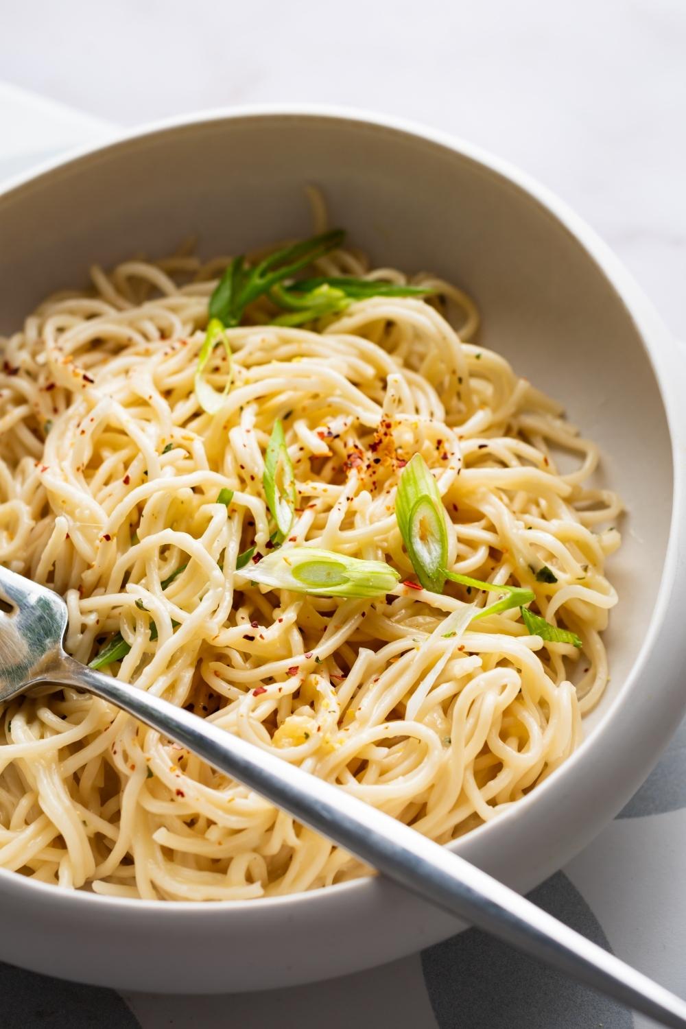 cheesy ramen in a white bowl with a fork