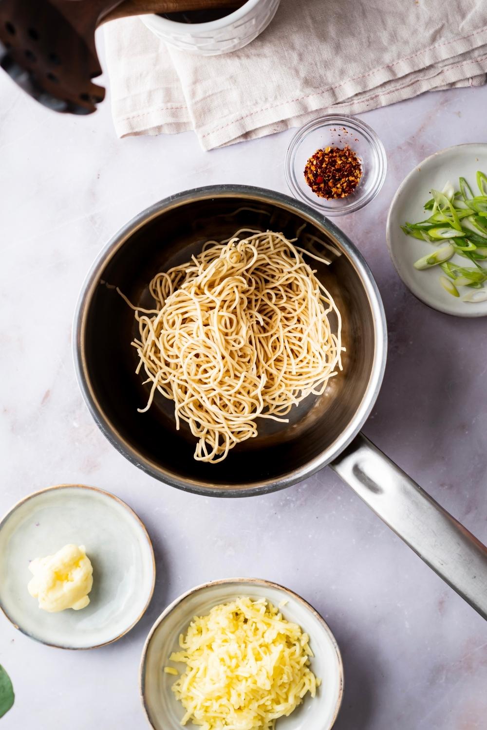 dry ramen noodles in a pot with prepared seasonings on the side