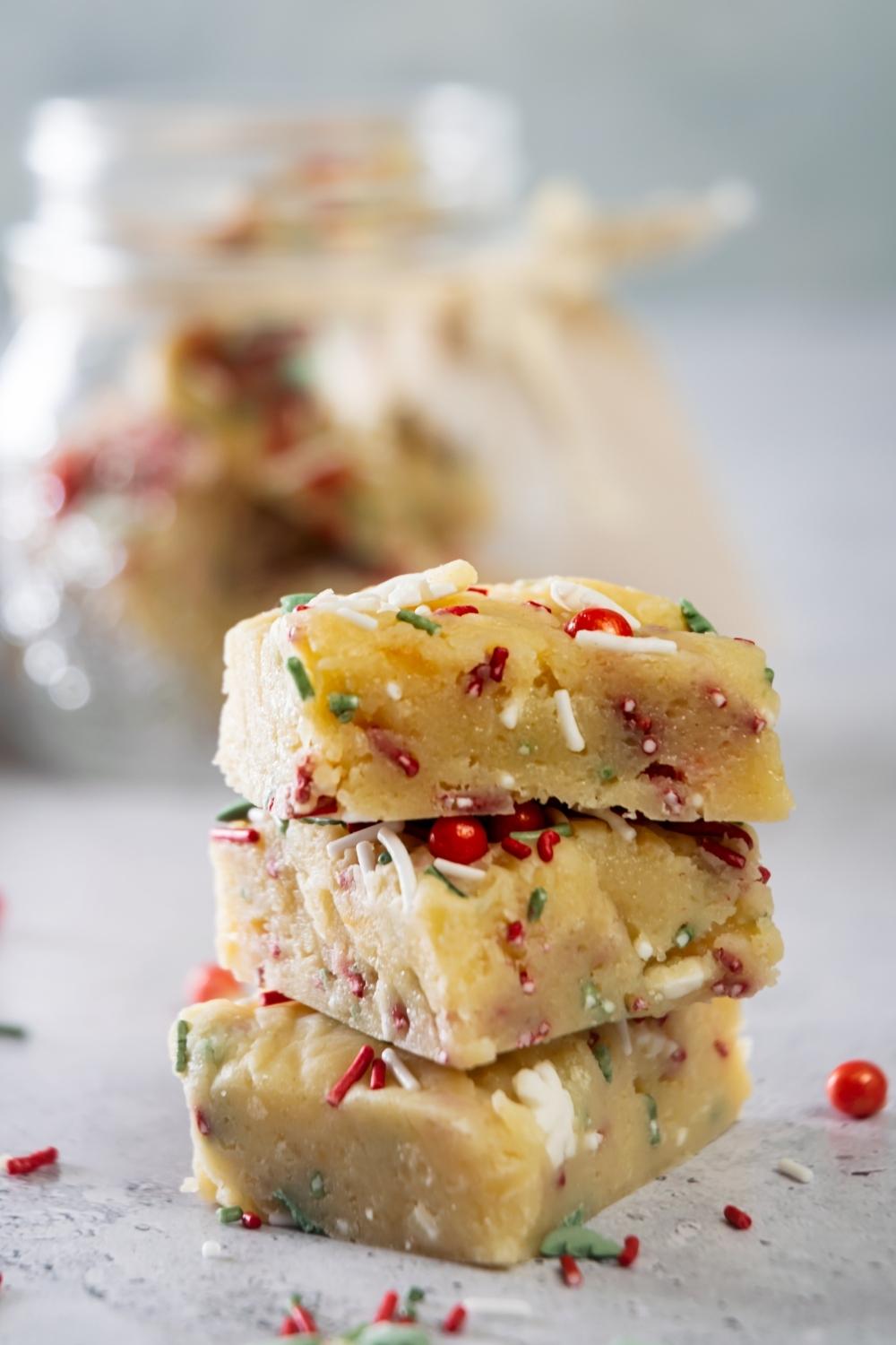stack of three pieces of sugar cookie fudge with christmas sprinkles