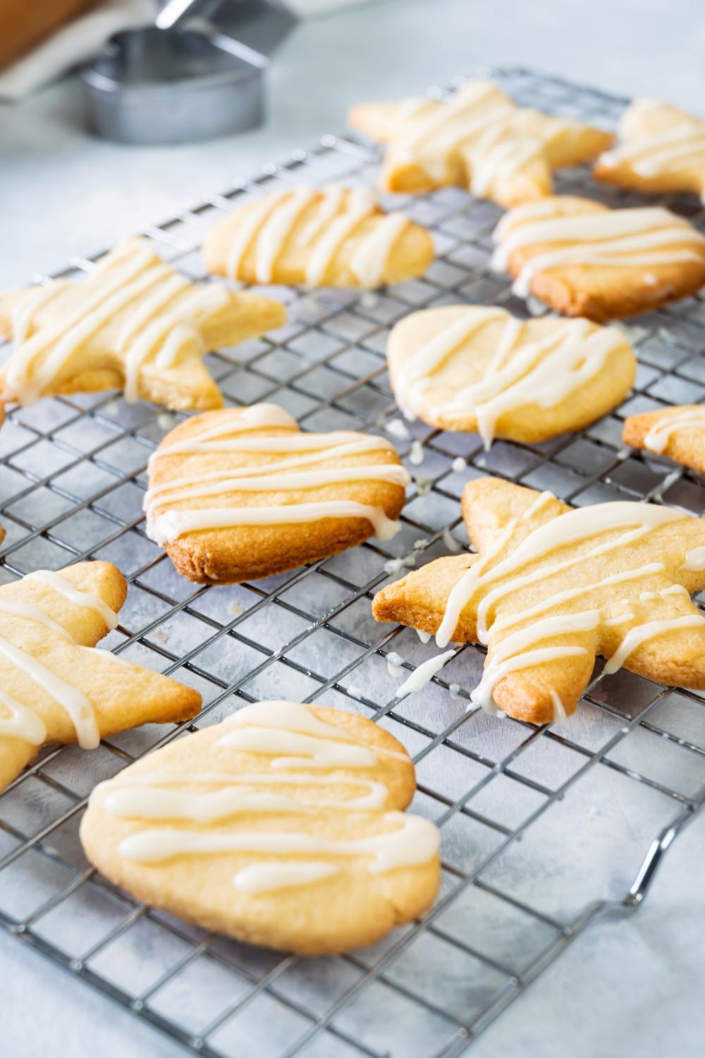 A cooling rack with baked cut out cookies drizzled with icing.