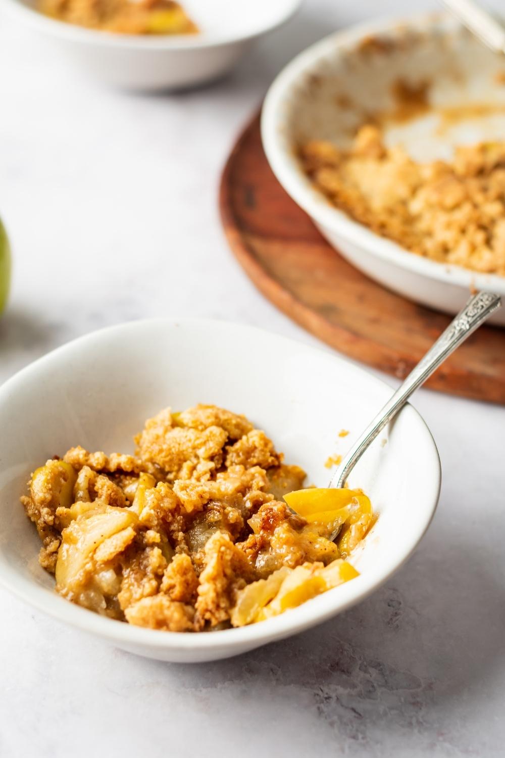 Apple crisp in a white bowl with a fork in it.