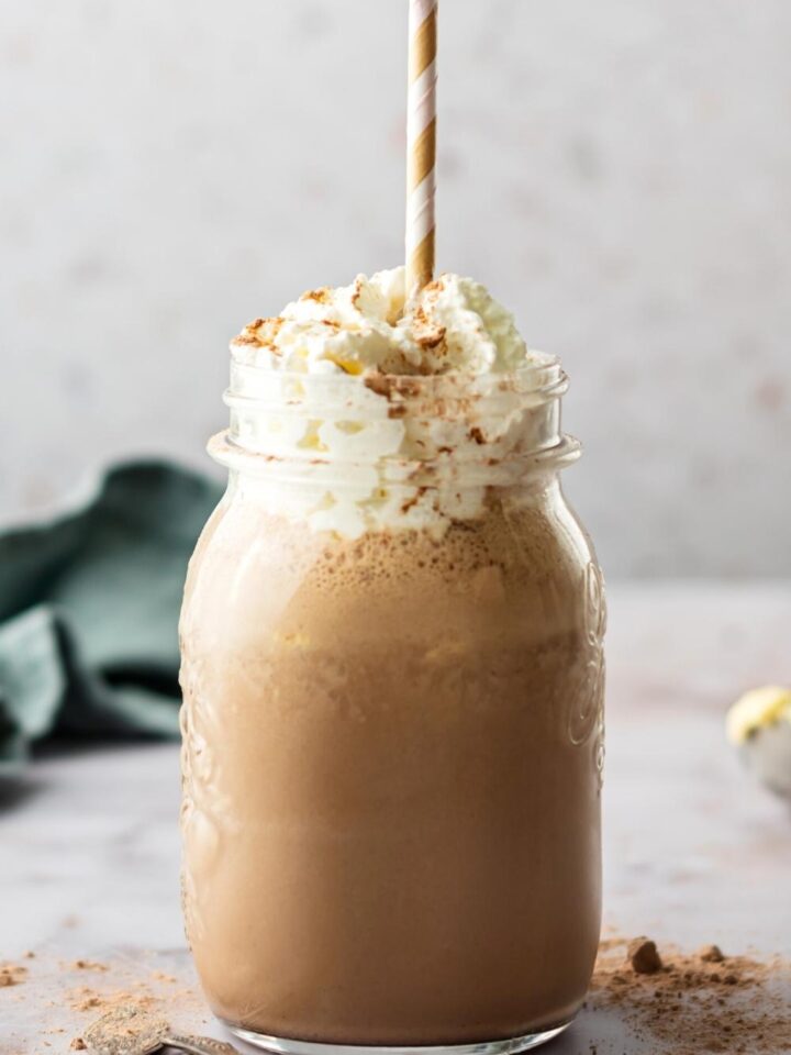 A chocolate milkshake in a glass with whipped cream.