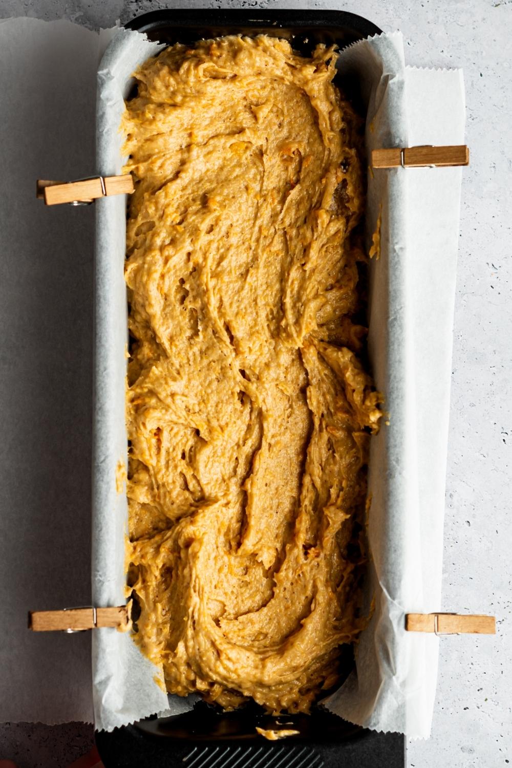 Sweet potato pound cake batter in a parchment she lined loaf pan.