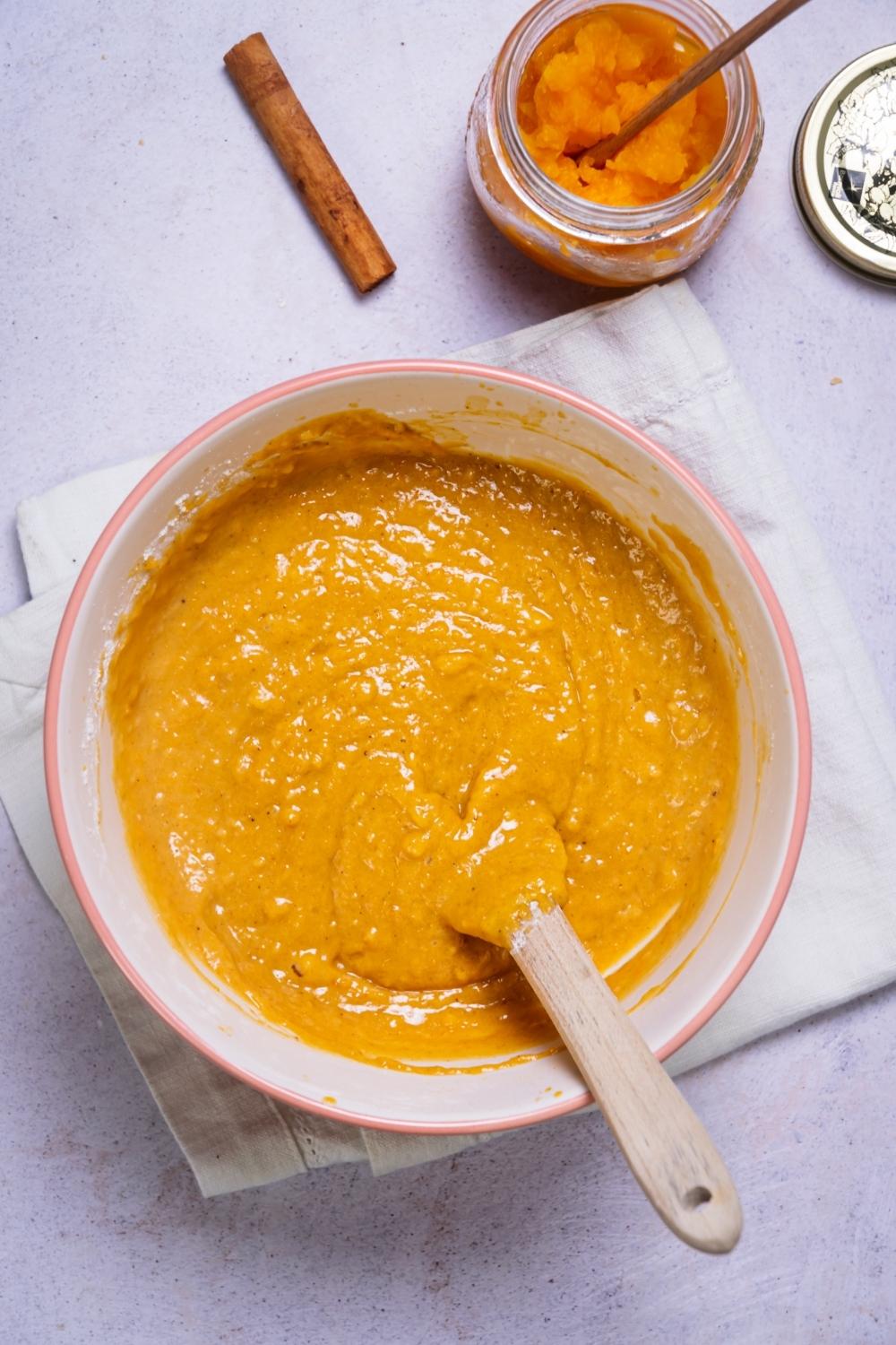 A bowl that is filled with pumpkin bread batter.